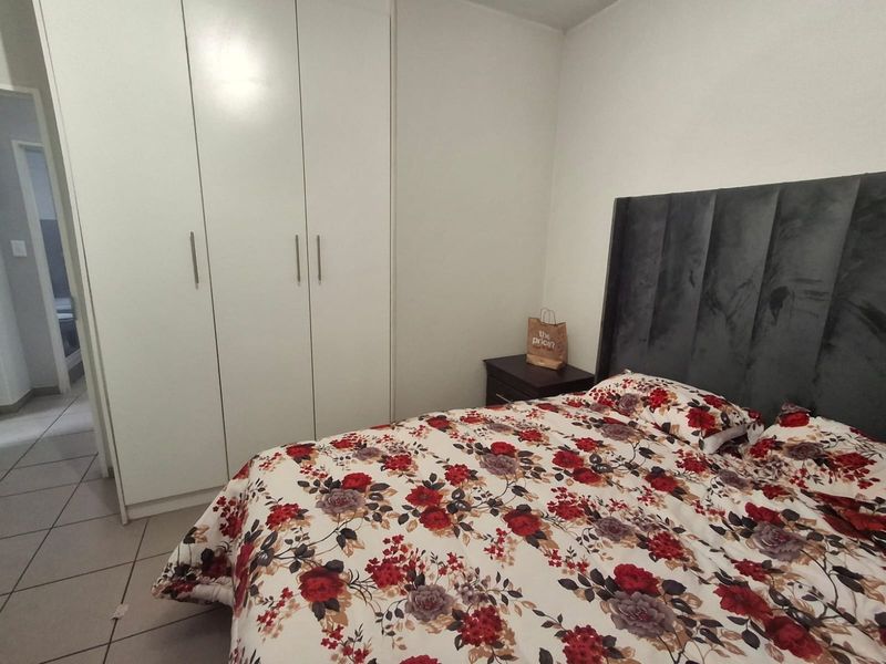 A functional bedroom featuring built-in cupboards and tiled flooring, providing a clean and practical living space.