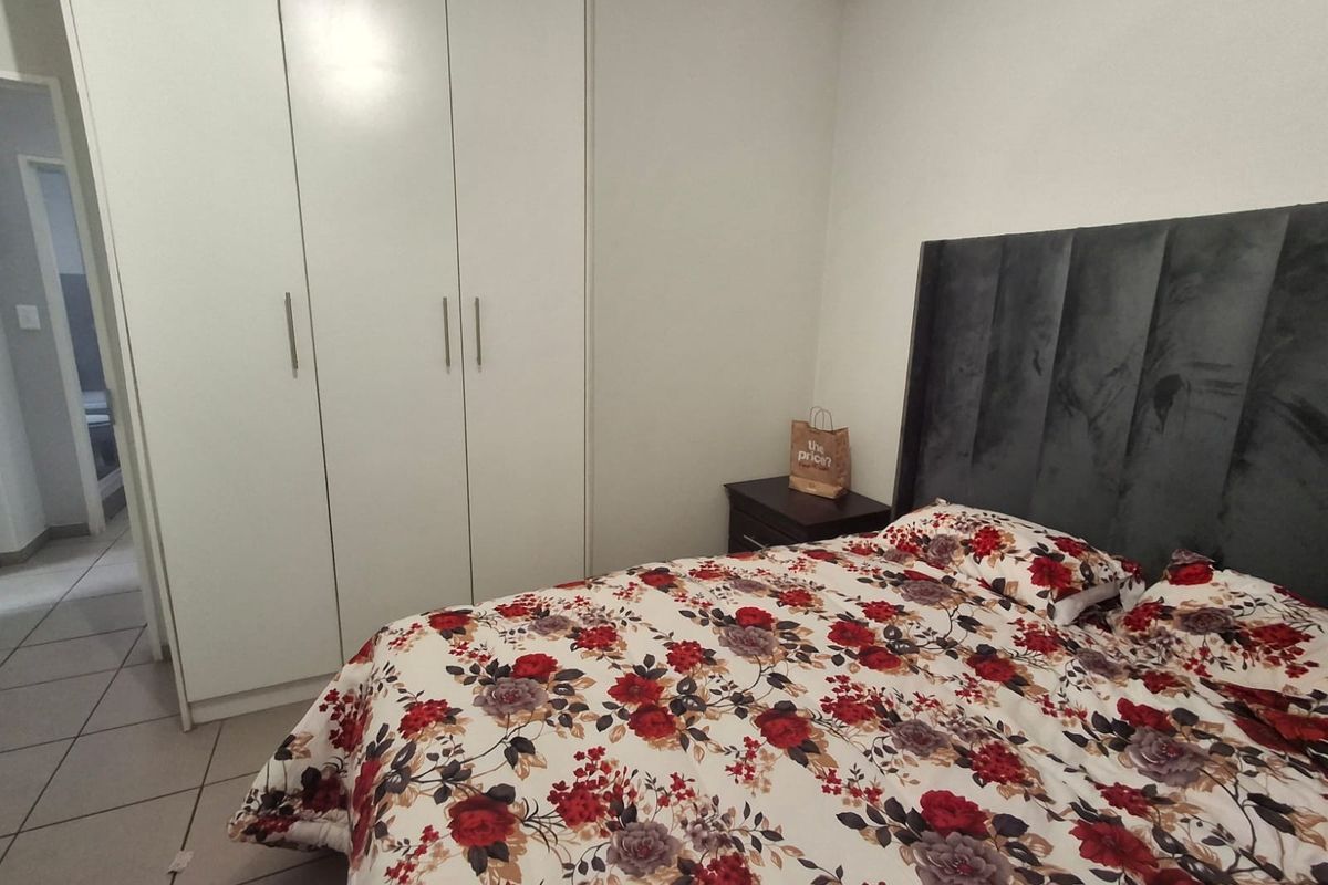 A functional bedroom featuring built-in cupboards and tiled flooring, providing a clean and practical living space.