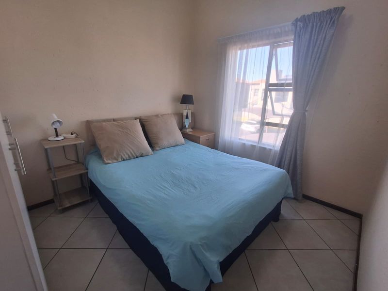 A functional bedroom featuring tiled flooring and a window with natural light, providing a comfortable space for rest.