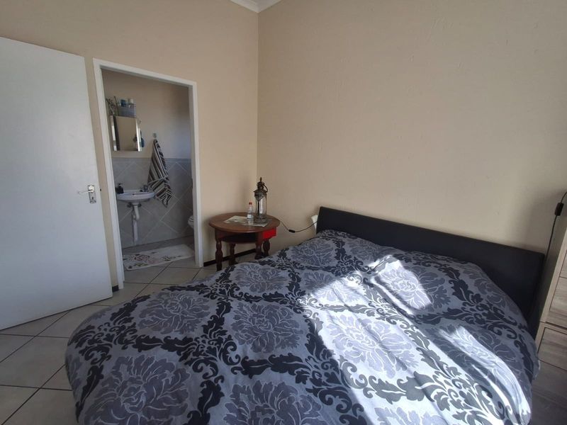 A bedroom featuring tiled flooring and direct access to an en-suite bathroom equipped with a pedestal basin.