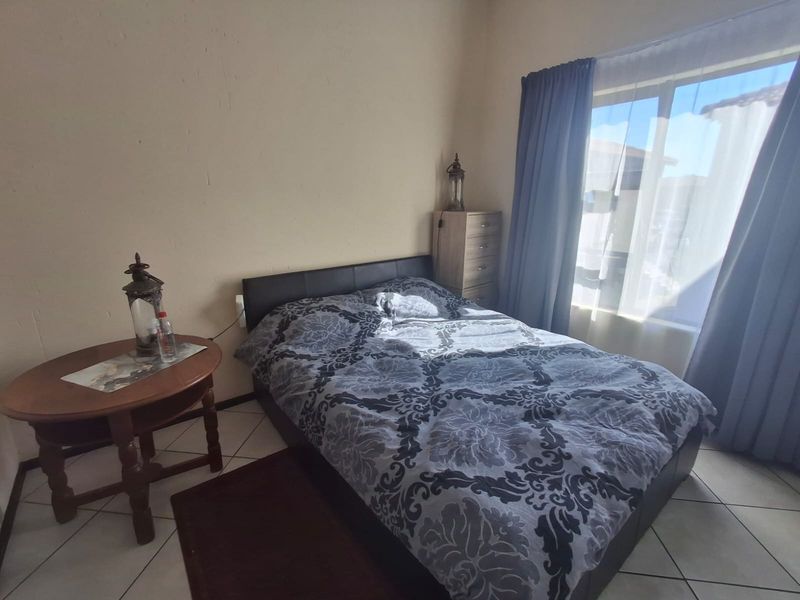 A functional bedroom featuring tiled flooring and a large window that allows for natural light.