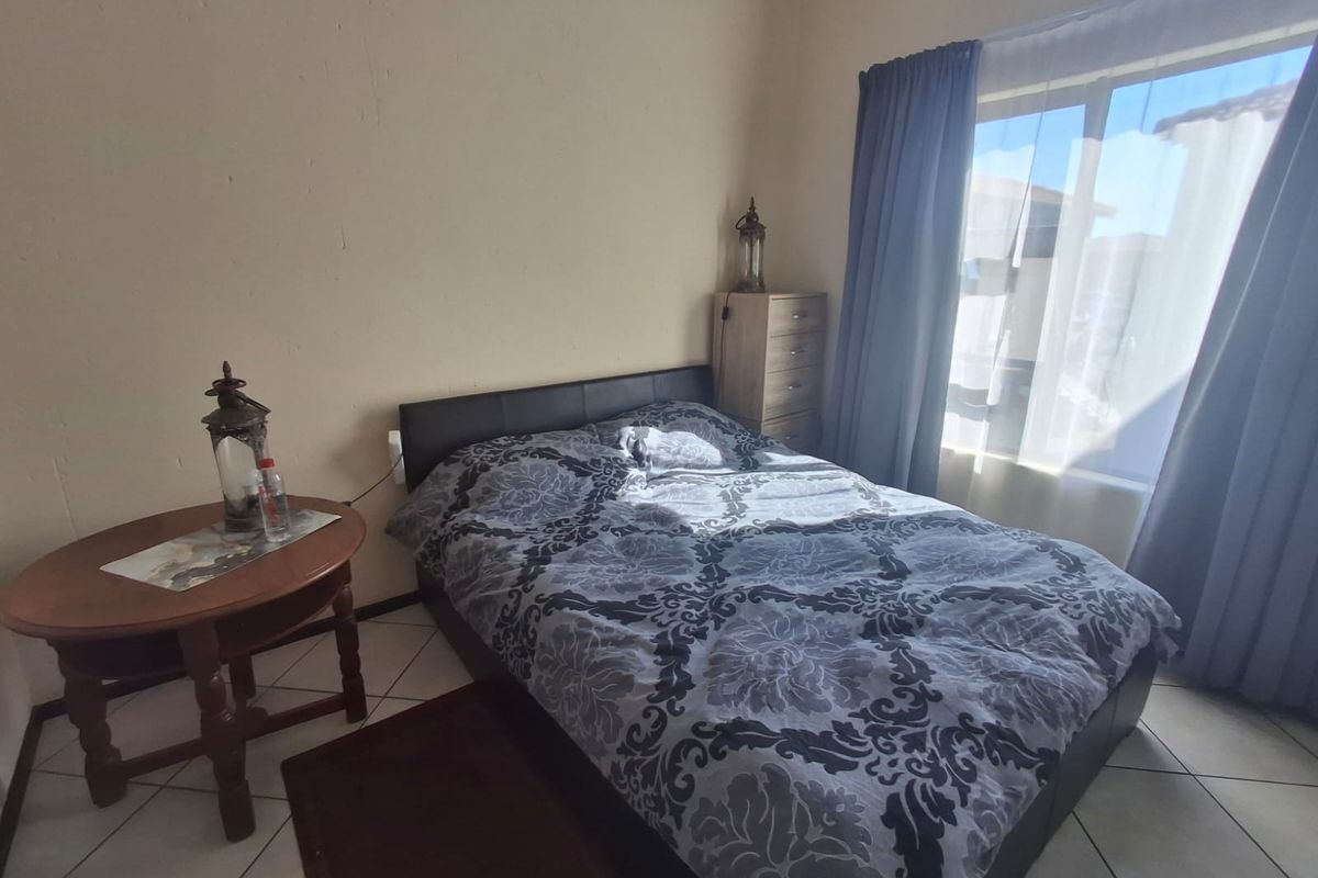 A functional bedroom featuring tiled flooring and a large window that allows for natural light.