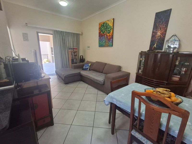 Open-plan living and dining area featuring tiled flooring and a sliding glass door providing access to an outdoor patio space.