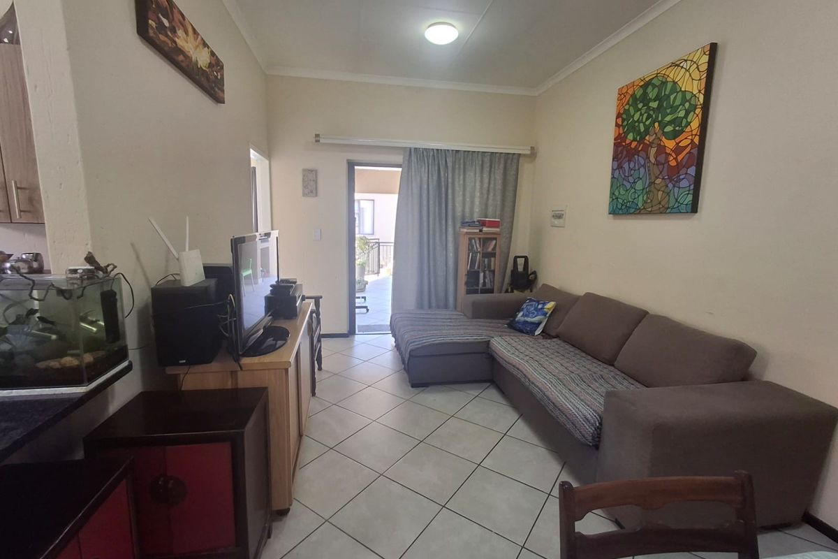 A living room area featuring tiled flooring and a sliding glass door providing access to an outdoor space.