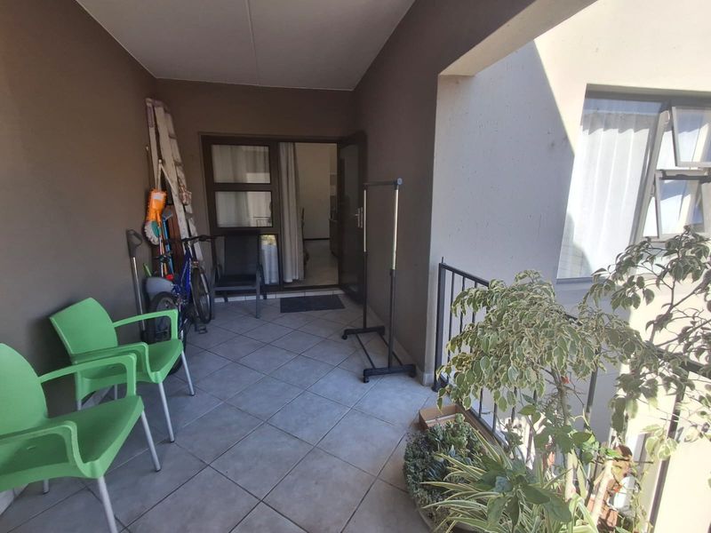 A covered balcony area featuring tiled flooring and a metal balustrade, providing an outdoor space accessible through a sliding door.