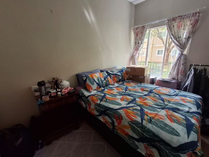 A functional bedroom featuring a large window that provides natural light and views of the surrounding complex.