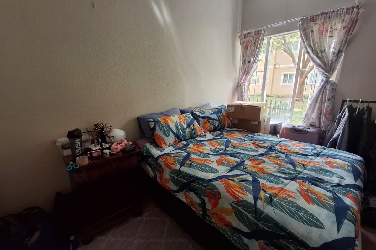 A functional bedroom featuring a large window that provides natural light and views of the surrounding complex.