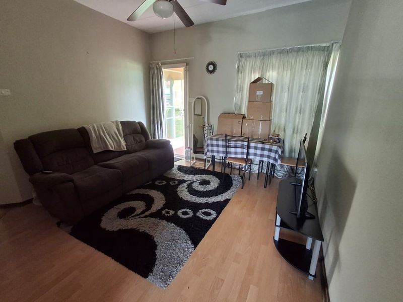 A living room featuring laminate flooring, a ceiling fan, and a sliding glass door providing access to the exterior.