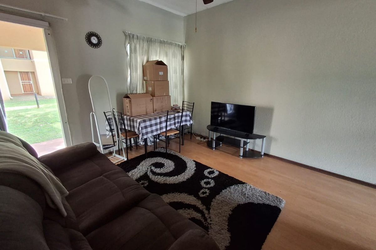 A living room featuring laminate flooring, a ceiling fan, and a sliding glass door providing access to the exterior.