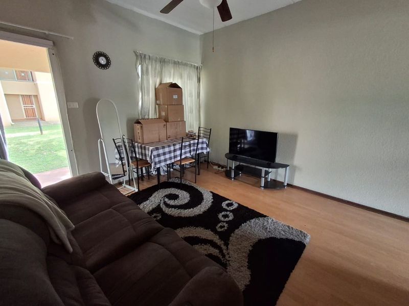 A living room featuring laminate flooring, a ceiling fan, and a sliding glass door providing access to the exterior.