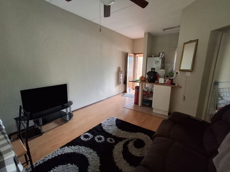 Open plan living area featuring laminate flooring, a ceiling fan, and a compact kitchen breakfast counter.