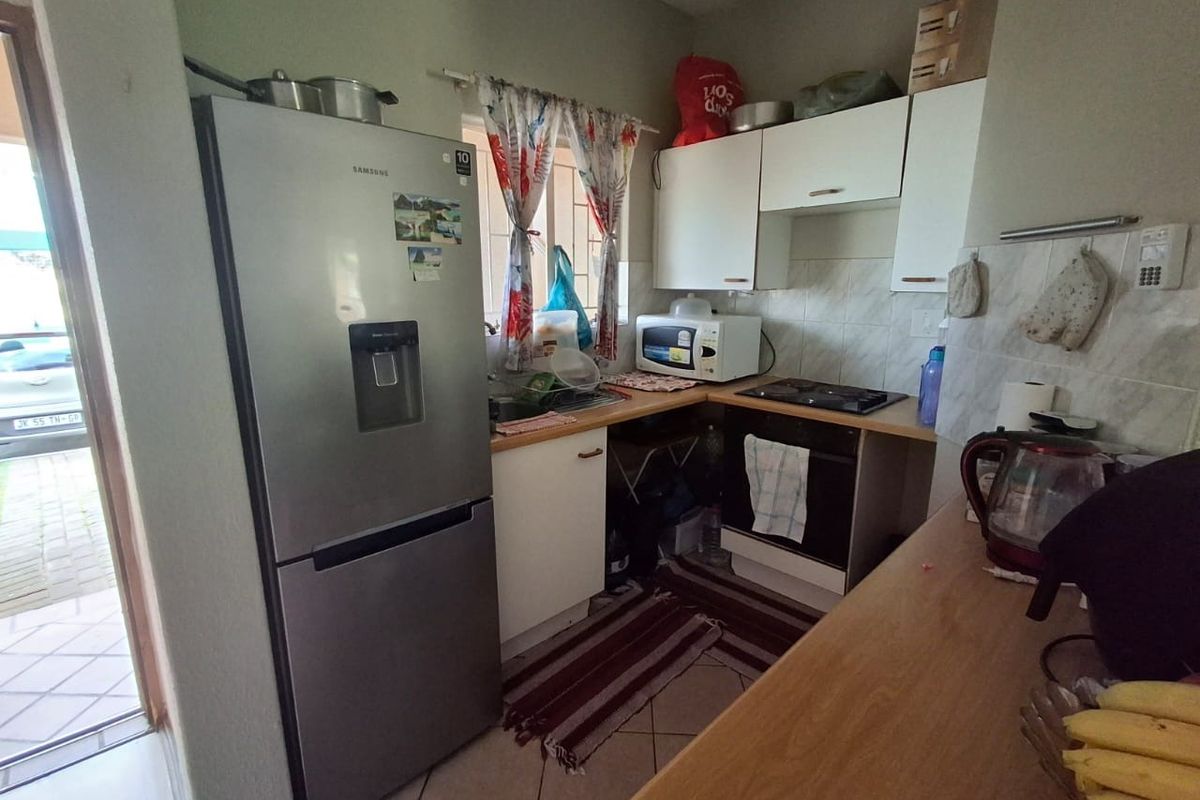 Compact kitchen featuring built-in cabinetry, laminate countertops, a built-in oven, and a hob, with tiled flooring and backsplash.