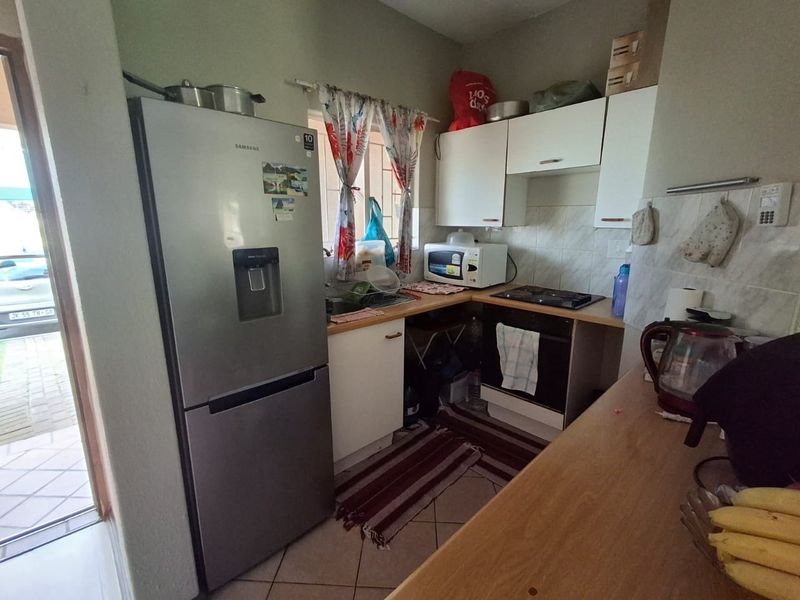 Compact kitchen featuring built-in cabinetry, laminate countertops, a built-in oven, and a hob, with tiled flooring and backsplash.