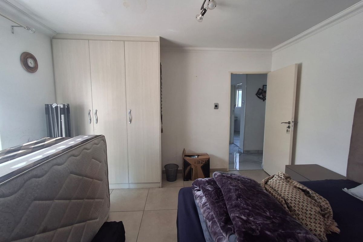 A bedroom featuring built-in cupboards, tiled flooring, and direct access to an adjoining bathroom.