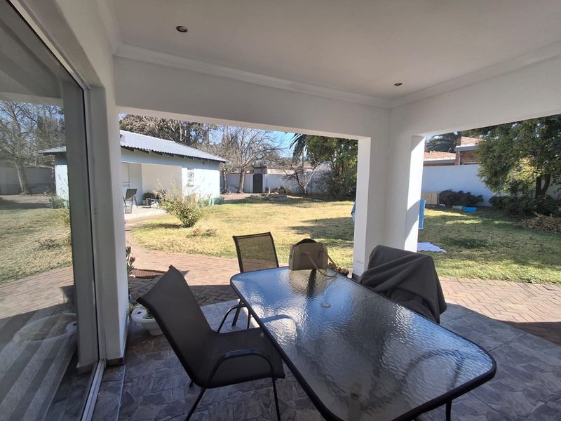 A covered patio area featuring tiled flooring and recessed lighting, providing direct access to the rear garden through large sliding glass doors.