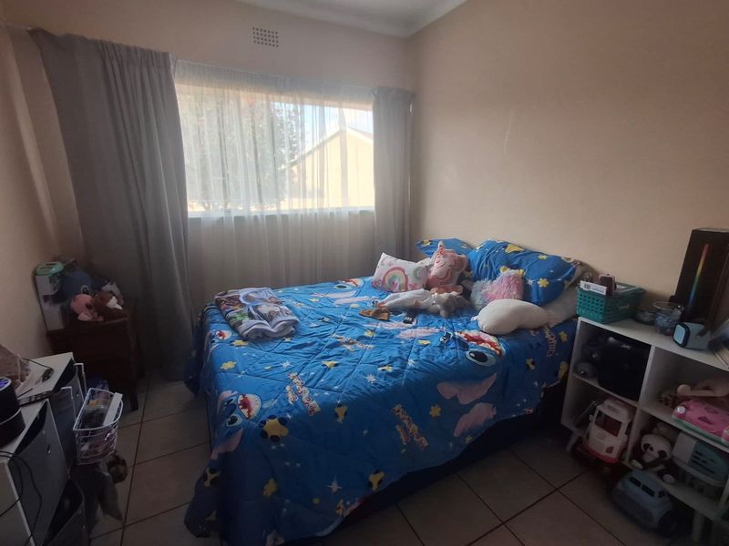 A standard bedroom featuring tiled flooring and a window with curtain tracks, providing a functional space for rest.