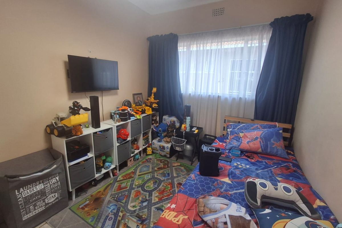 A standard bedroom featuring neutral wall paint, a window with curtain rails, and a ceiling vent, providing a functional space for a child's room.