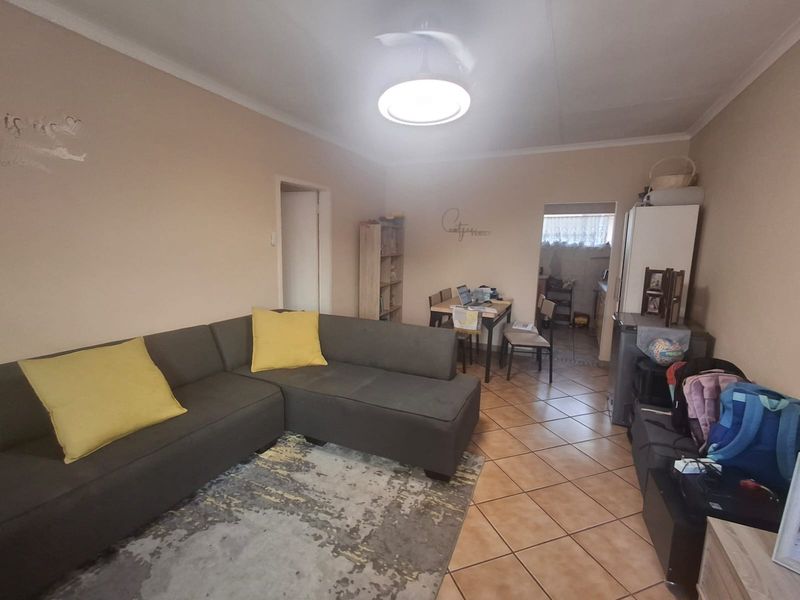 Open plan living and dining area featuring ceramic floor tiles and a central ceiling fan, connecting to a secondary kitchen or utility space.