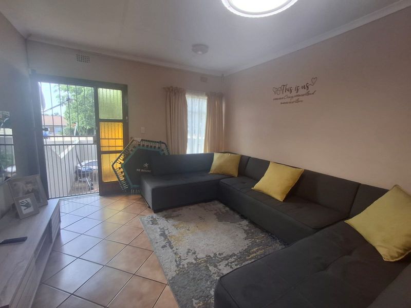 A living room featuring tiled flooring, a sliding security gate leading to the exterior, and neutral wall finishes.