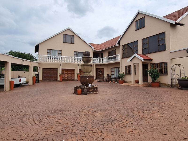 Spacious paved courtyard featuring a central stone fountain, covered parking bays, and a multi-level residential facade with balcony and garage access.