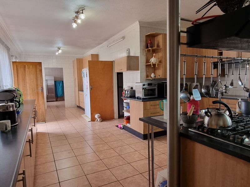 Spacious kitchen featuring wooden cabinetry, a gas hob with extractor fan, and tiled flooring, offering a functional layout with ample counter space.