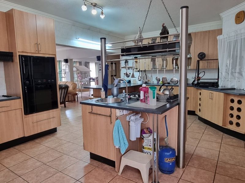 Spacious kitchen featuring light wood cabinetry, a central island with a prep sink, integrated oven, and ample counter space, opening into the living area.