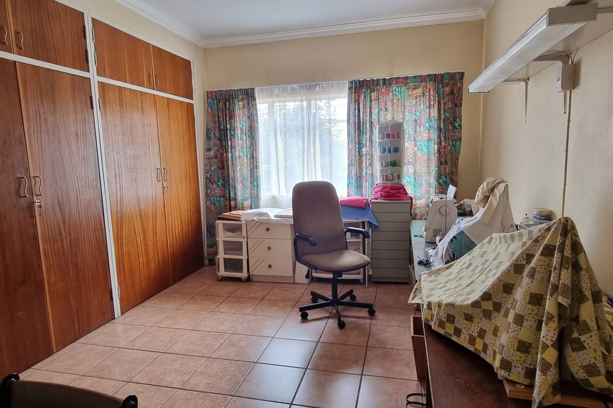 A functional bedroom featuring extensive built-in wooden cabinetry, tiled flooring, and large windows allowing for natural light.