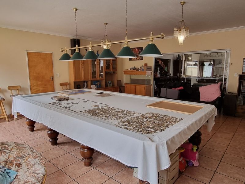 Spacious living area featuring tiled flooring, built-in cabinetry, and a multi-pendant light fixture, suitable for a games room or entertainment space.
