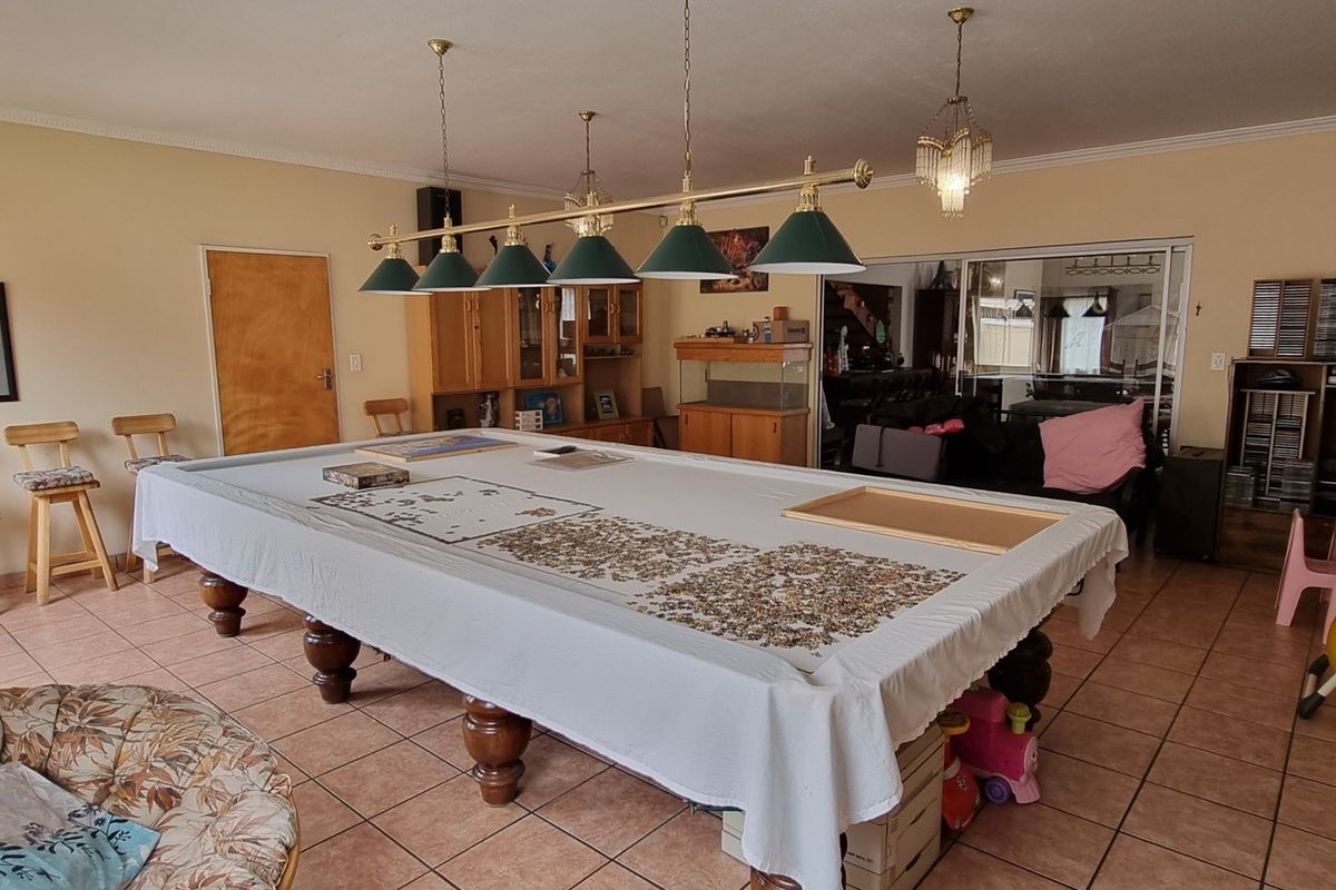 Spacious living area featuring tiled flooring, built-in cabinetry, and a multi-pendant light fixture, suitable for a games room or entertainment space.