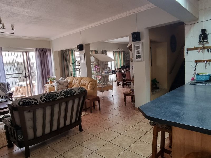 Open plan living area featuring a kitchen breakfast bar, tiled flooring, and direct access to an outdoor patio through sliding glass doors.