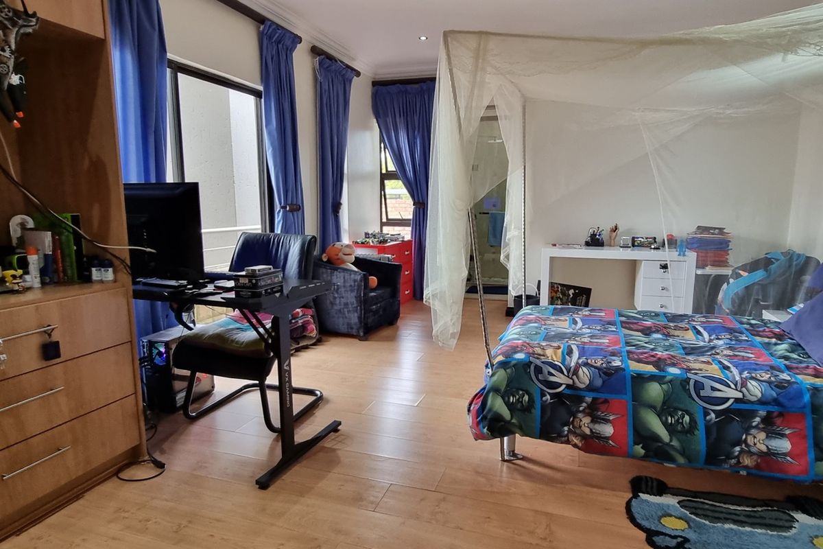 Spacious bedroom featuring wood-look tile flooring, large windows with curtains, and an en-suite bathroom access.
