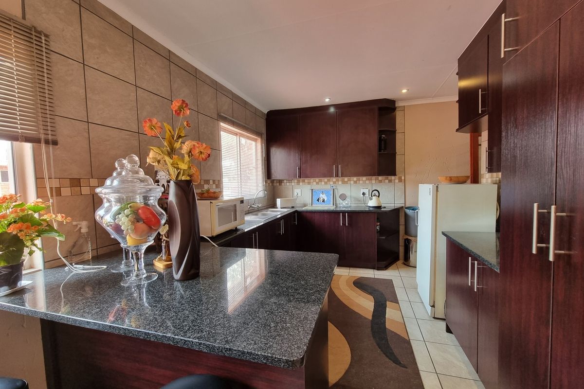 A functional kitchen featuring dark wood cabinetry, granite countertops, a breakfast nook, and tiled splashbacks, offering ample storage and workspace.