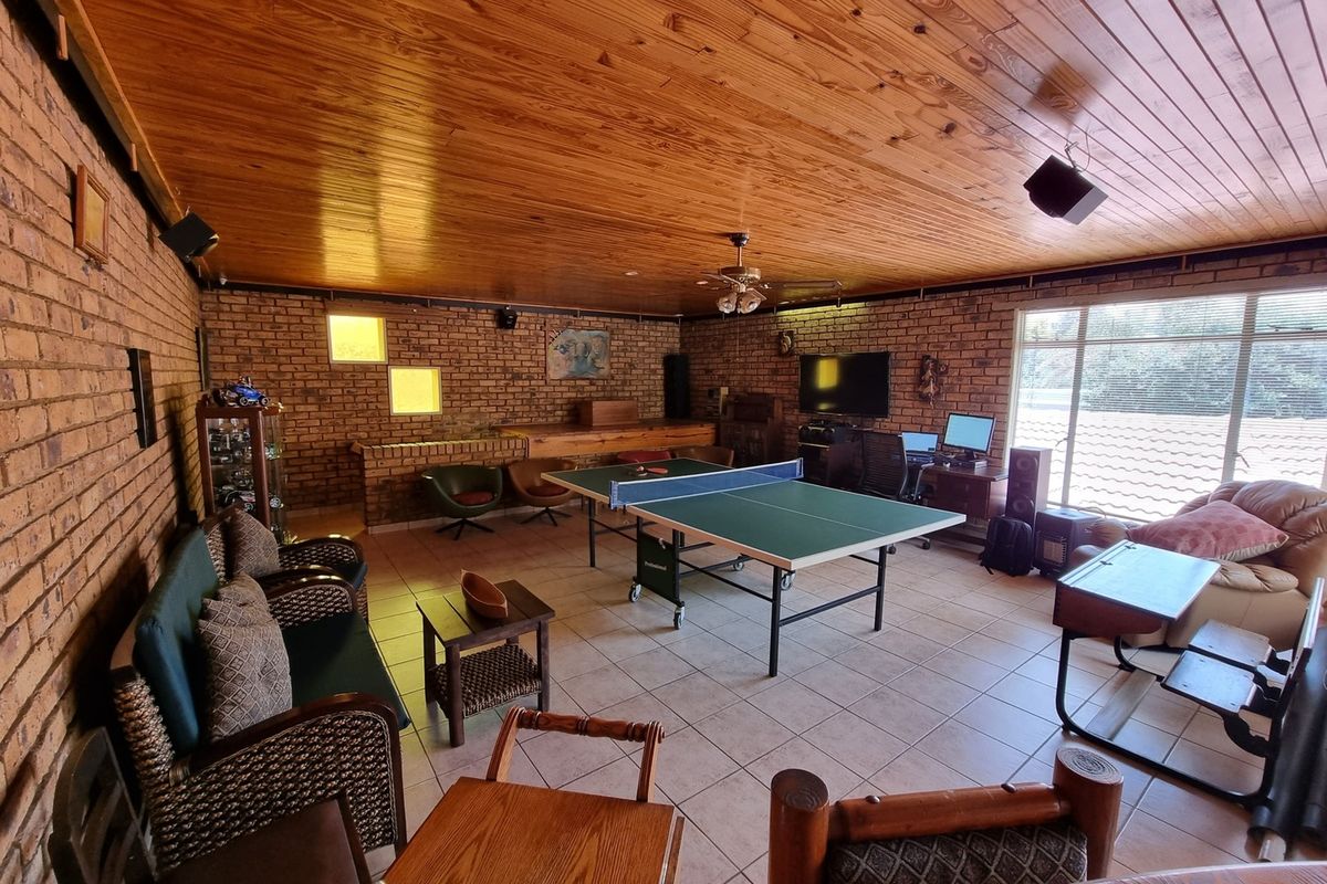 Spacious living area featuring exposed brick walls, tiled flooring, and a timber-clad ceiling, suitable for a multi-purpose entertainment or recreation room.