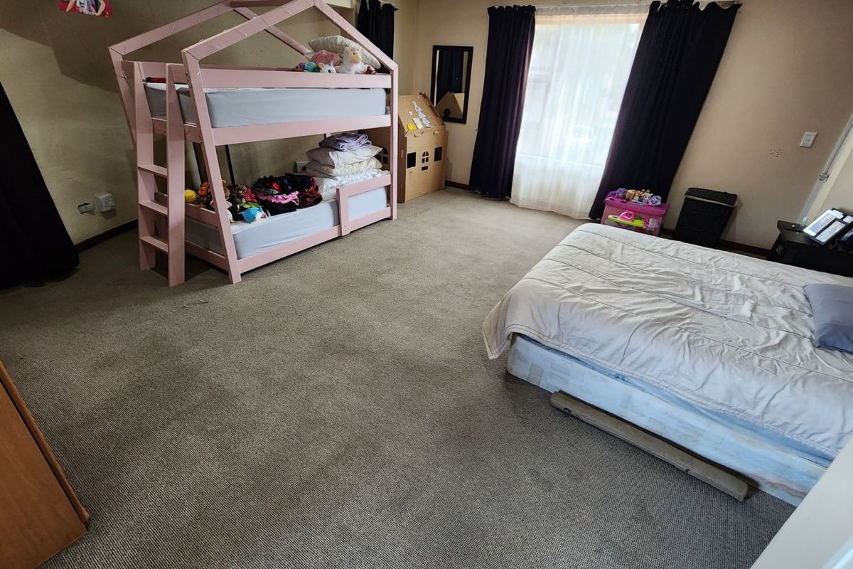 Spacious bedroom featuring neutral wall tones and carpeted flooring, offering a versatile layout for various furniture arrangements.