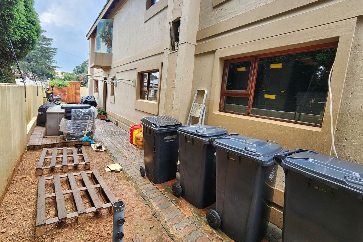 Rear exterior view of the property showing a paved side path, timber window frames, and general maintenance areas.