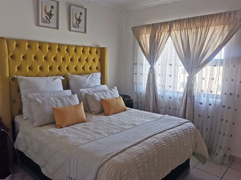 A well-maintained bedroom featuring tiled flooring and large windows with installed curtain rails, providing ample natural light.