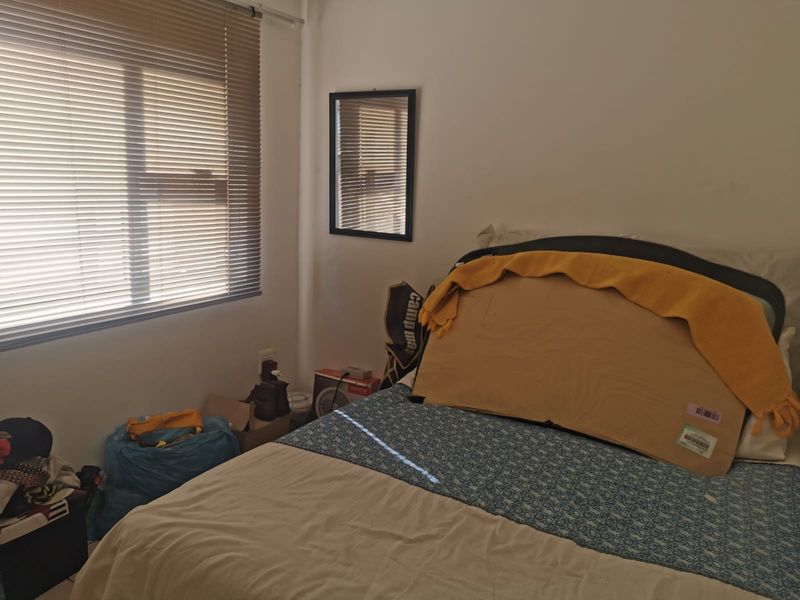A bedroom featuring a window with venetian blinds and neutral wall finishes, providing a functional space for rest.