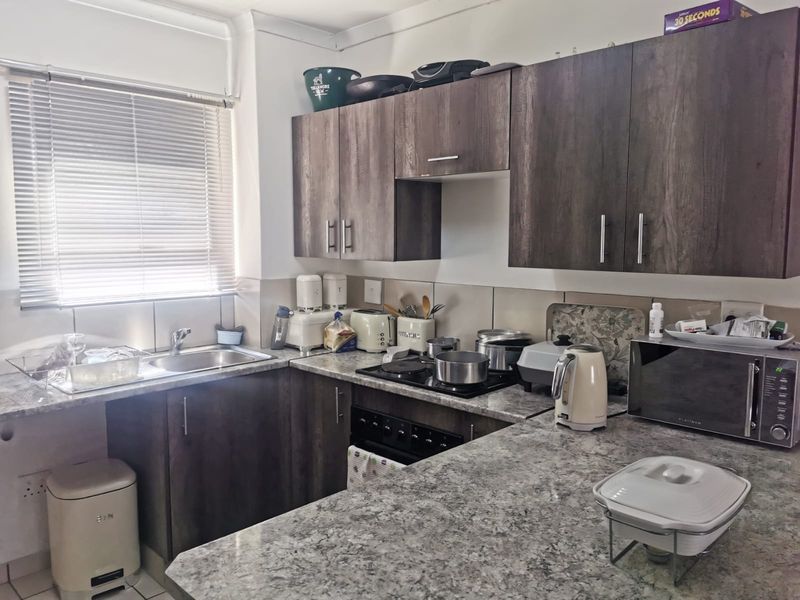 Functional kitchen featuring dark wood-look cabinetry, granite countertops, tiled backsplash, and integrated cooking appliances, offering a practical layout for daily meal preparation.
