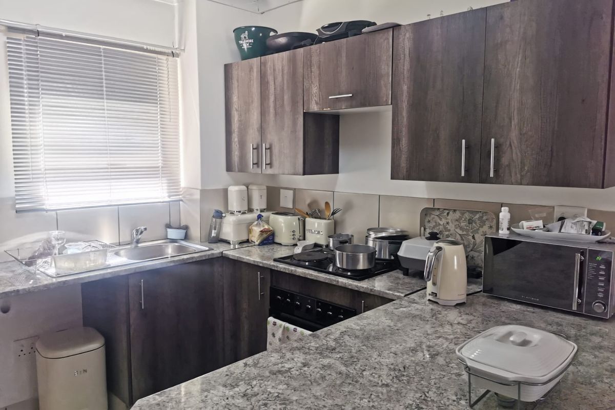 Functional kitchen featuring dark wood-look cabinetry, granite countertops, tiled backsplash, and integrated cooking appliances, offering a practical layout for daily meal preparation.