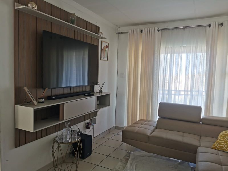 A cozy living room featuring a modern slatted wood feature wall with a built-in media console and tiled flooring.