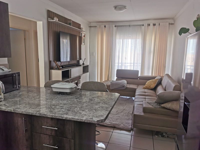Open-plan living area featuring a kitchen island with granite countertops, tiled flooring, and a built-in media unit, creating a functional and connected living space.