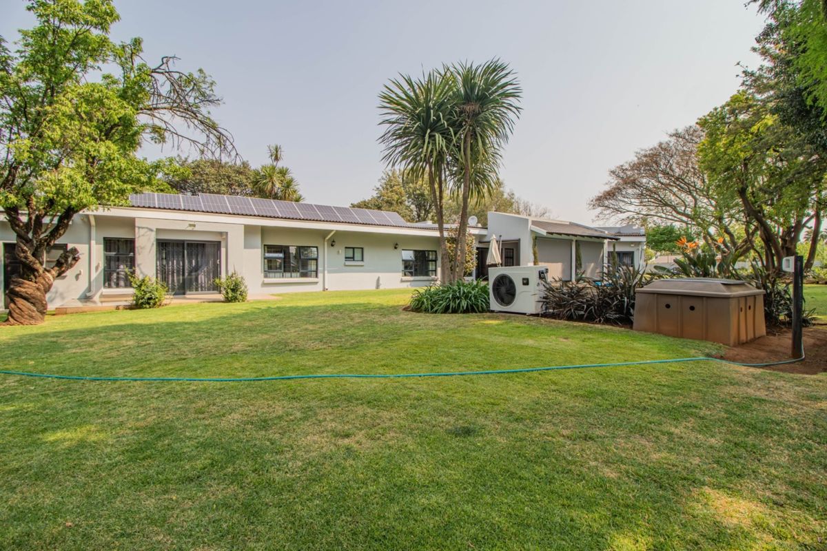 Spacious rear garden featuring a well-maintained lawn, solar panel installation on the roof, and integrated outdoor utility infrastructure.