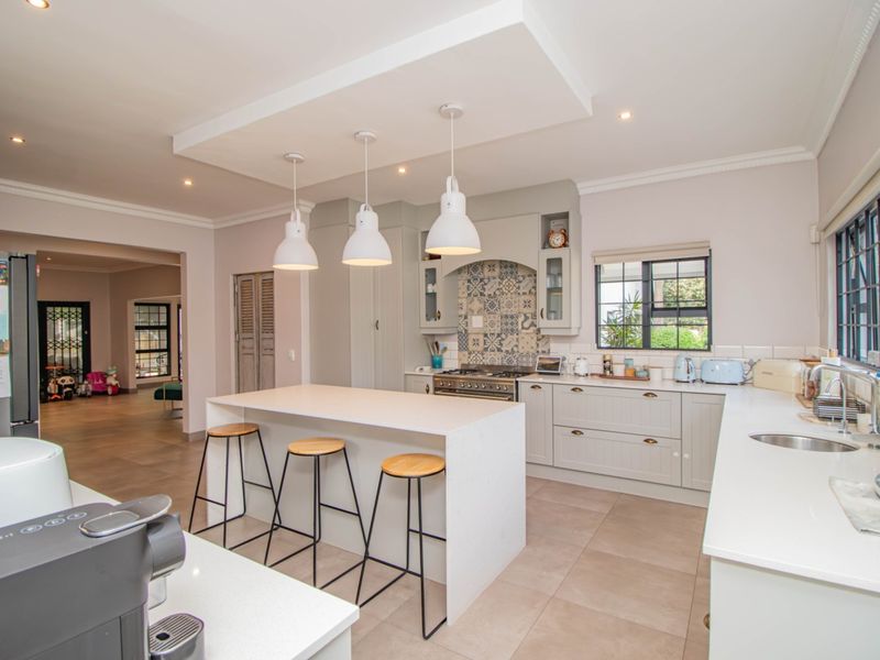 Modern kitchen featuring a central island with breakfast bar, stone countertops, gas stove, decorative tiled splashback, and ample built-in cabinetry.