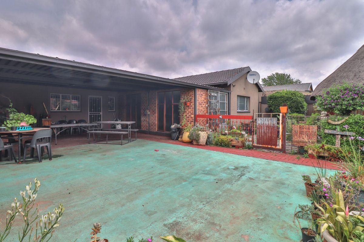 Rear exterior view featuring a covered patio area with brick facade and paved flooring, offering potential for outdoor entertainment space improvement.