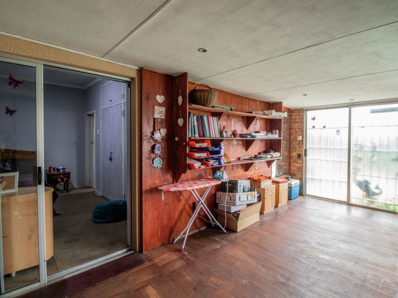 A living area featuring built-in wooden shelving, exposed brick accents, and sliding glass doors that provide access to the exterior.