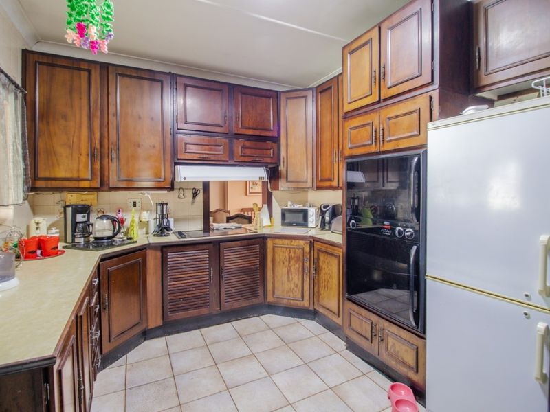 A functional kitchen featuring traditional wooden cabinetry, tiled flooring, and built-in oven, offering a classic layout with ample storage space.
