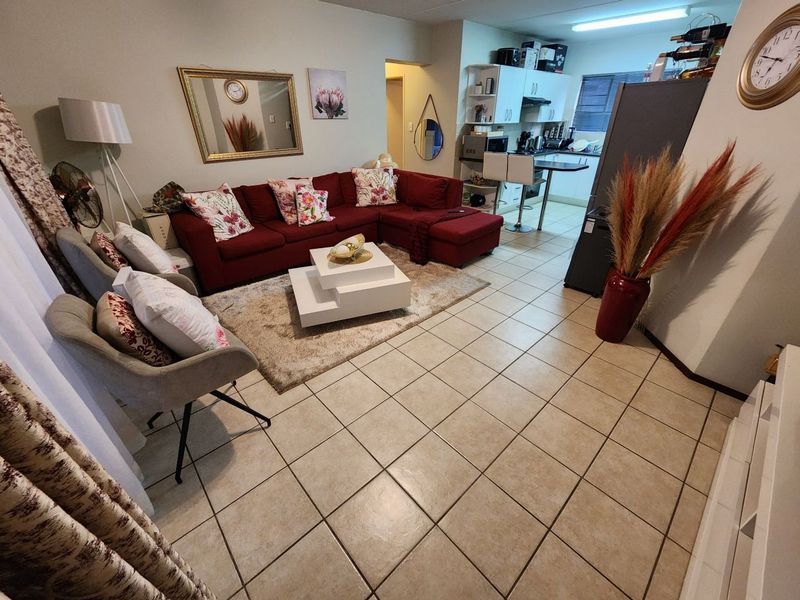 Open-plan living area featuring tiled flooring and a compact kitchen with built-in cabinetry and a breakfast counter.
