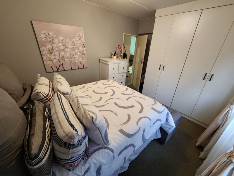 A bedroom featuring neutral wall tones and ample built-in cupboard storage space.