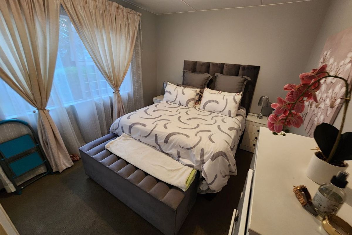 A functional bedroom featuring carpeted flooring and large windows with installed curtain tracks, providing natural light and a neutral base for interior design.