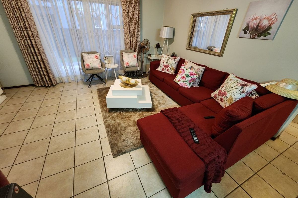 A comfortable living room featuring tiled flooring and a large sliding glass door that provides access to the outdoor area.